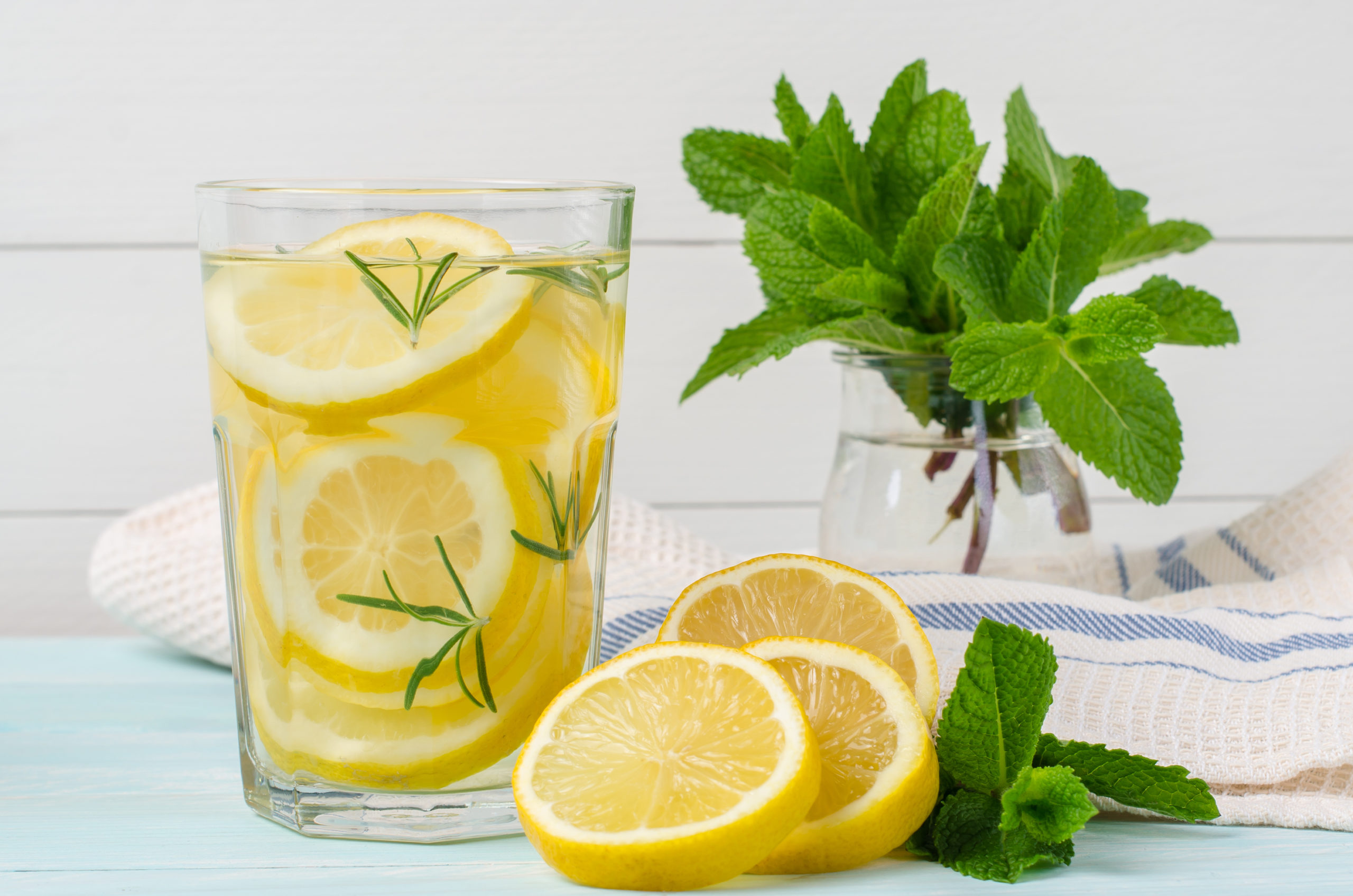 Summer fruit drink on wooden background. Cold lemonade with ice. Detox citrus infused flavored water. Refreshing summer homemade cocktail with lemon. Fresh lemon and lemonade